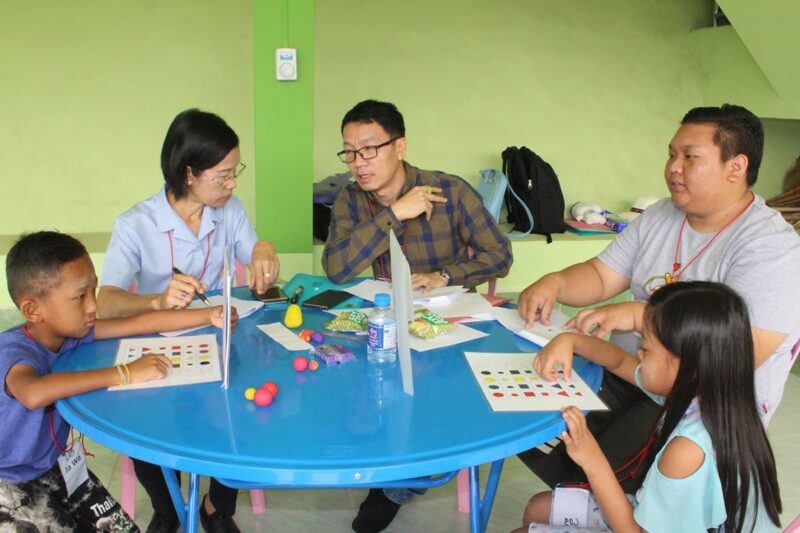 Children and their cleft care team sat around a blue table while doing an exercise