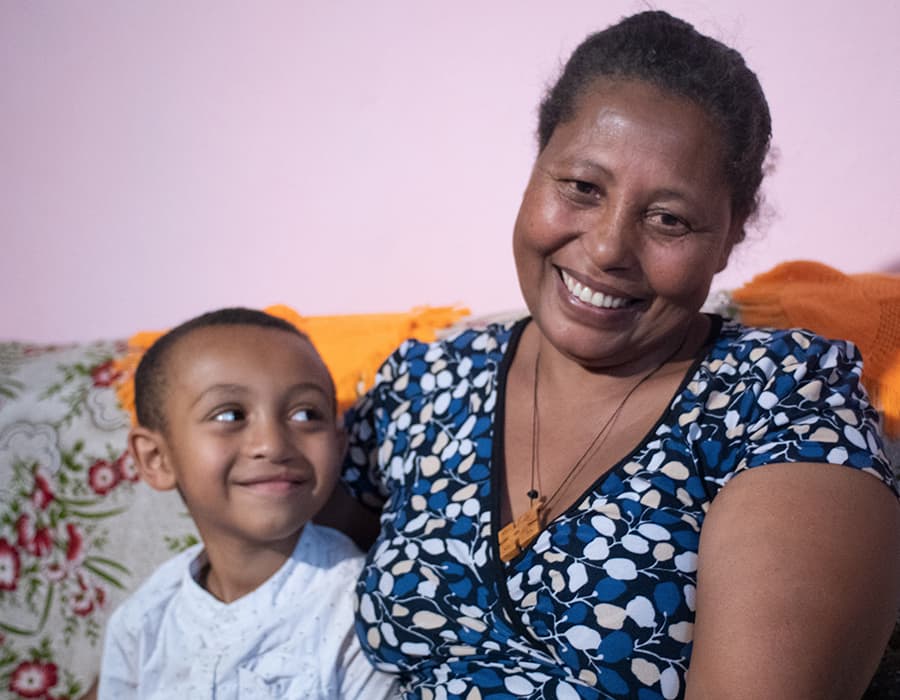 cc-at-a-glance Smiling son looking at smiling mother while they are sat on a couch