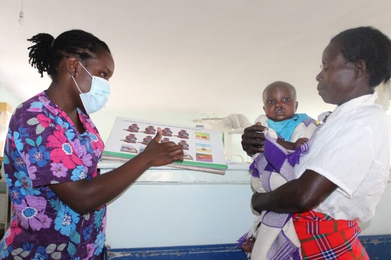 Nurse educating mother through a diagram, while she is holding her son