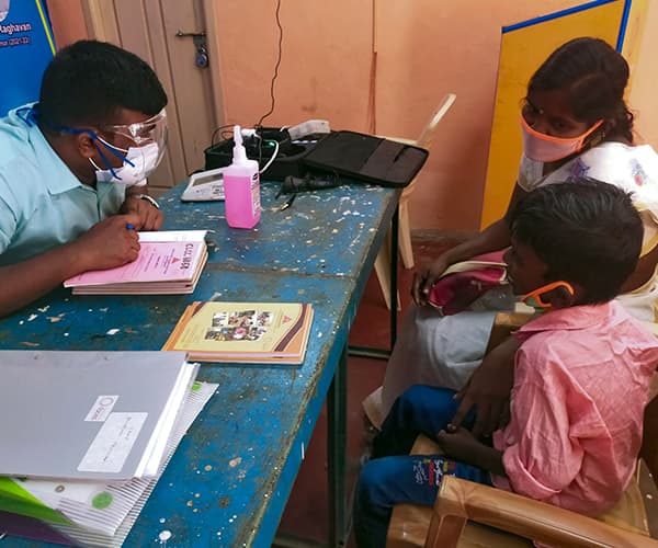 A child with a cleft palate and his mother are sitting and talking with a doctor and wearing face masks.