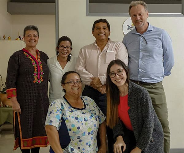 A group of six adults in a healthcare setting smiling at the camera.