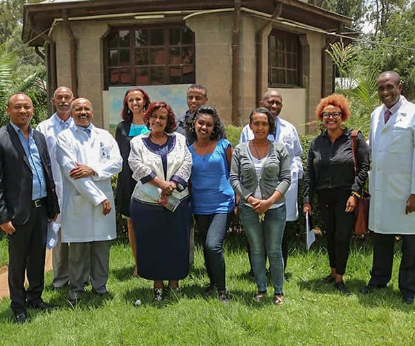 A group of Ethiopian medical professionals standing on the grass and smiling at the camera.