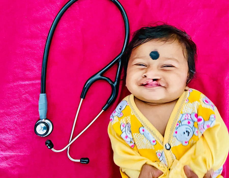 why-obstacles A child with cleft lip laying down beside a stethoscope on a pink background